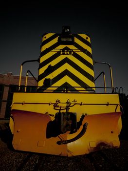 Vintage yellow locomotive at front of the roundhouse.