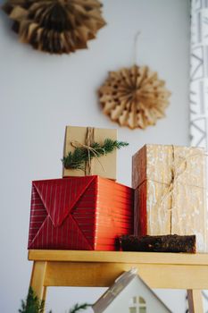 A red box with gold stripes, a kraft box with splashes of paint and a box with a coniferous branch. Blue flashlights in defocus on the background. Colorful gift boxes for the Christmas holidays.