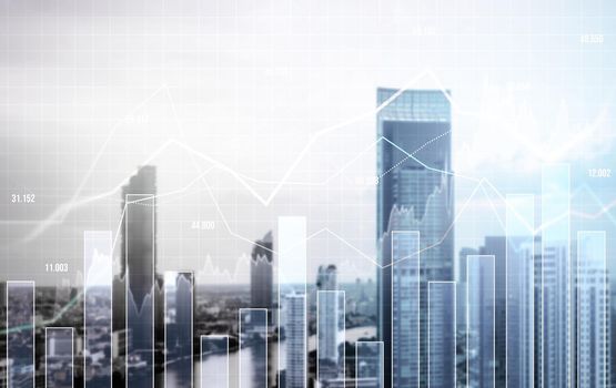 As background for a financial or business concept, digital screen and financial graphs overlap on a picture of modernistic cityscape, skyscrabbers.