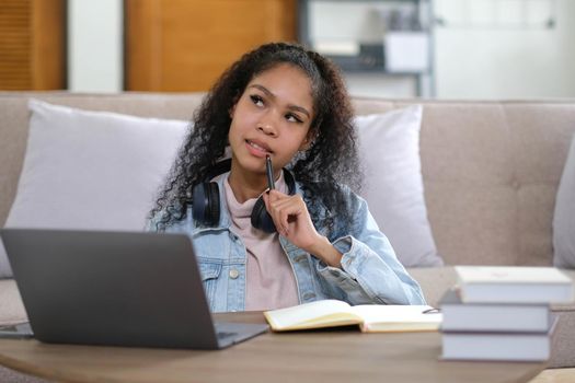 Focused african american girl student wearing headphones looking at laptop watching online webinar training course, serious mixed race woman learning english language on computer, internet e-learning.