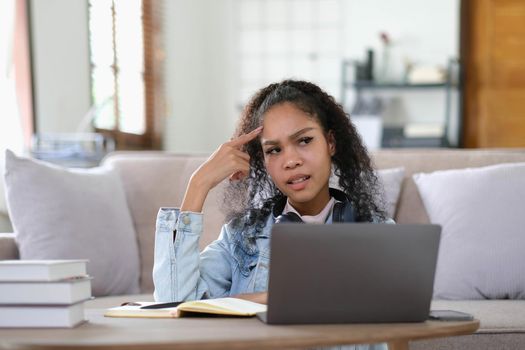 Exhausted female student feeling headache from problems with university course work connected to wifi for browsing informative websites, unhappy dark skinned woman tired from e learning on laptop.