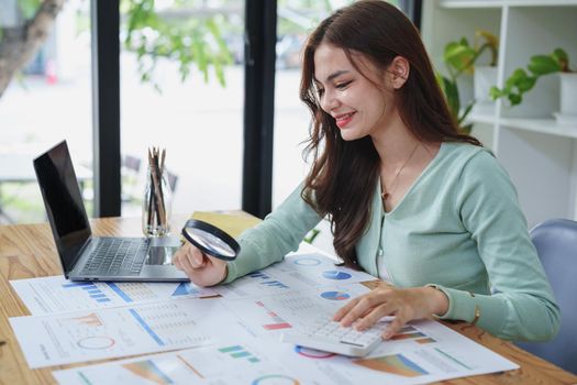 A half-bred girl, an audit employee, an accountant holding a magnifying glass and using a calculator to check the financial statement documents to calculate the annual tax payment to the IRS.