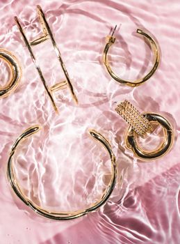 Jewellery branding, fashion gift and luxe shopping concept - Golden bracelets, earrings, rings, jewelery on pink water background, luxury glamour and holiday beauty design for jewelry brand ads