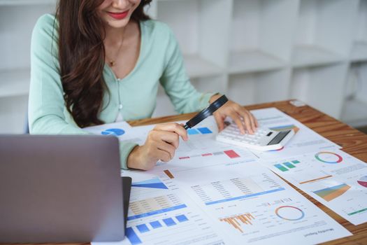 A half-bred girl, an audit employee, an accountant holding a magnifying glass and using a calculator to check the financial statement documents to calculate the annual tax payment to the IRS.