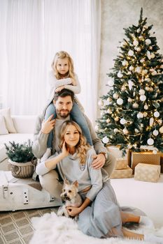 Happy family: mom, dad and pet. Family in a bright New Year's interior with a Christmas tree.