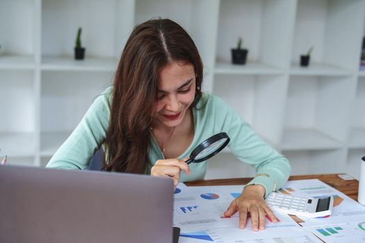 A half-bred girl, an audit employee, an accountant holding a magnifying glass and using a calculator to check the financial statement documents to calculate the annual tax payment to the IRS.