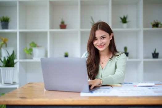 A portrait of a half girl showing a smiling face using a computer and financial budget documents at her office desk