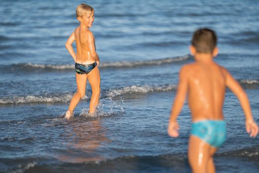 Two little boys having fun on the water, happy kids enjoying on the beach resort, summer concept holiday, Emilia Romagna, Italy.