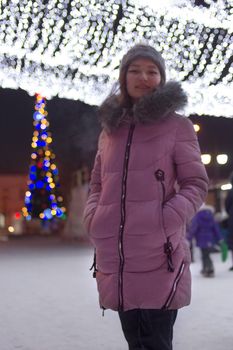 Young woman on central downtown with christmas tree and lights at night, sky festive illumination shine and glow, urban holiday, vertical defocus image