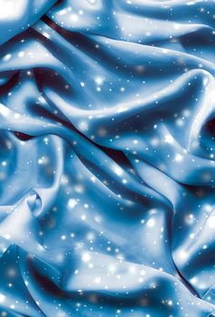 Winter fashion, shiny fabric and glamour style concept - Magic holiday blue soft silk flatlay background texture with glowing snow, luxury beauty abstract backdrop