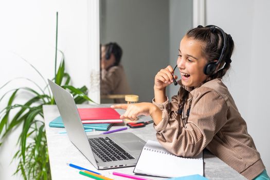 Online Education. Cute little Girl Study At Home With Laptop And Wireless Headphones, Adorable Kid Having Web Lesson With Teacher, Enjoying Distance Learning During Quarantine Time, Free Space.