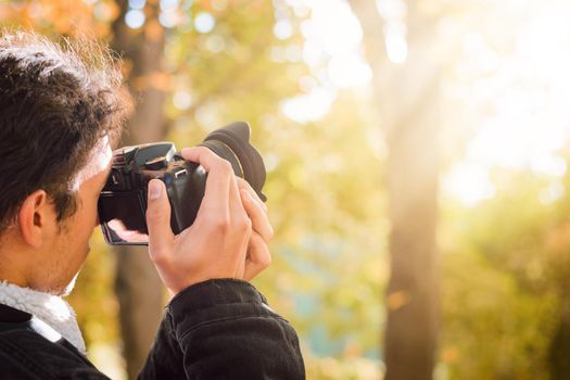 Student taking pictures of a fall forest with a bright sunlight