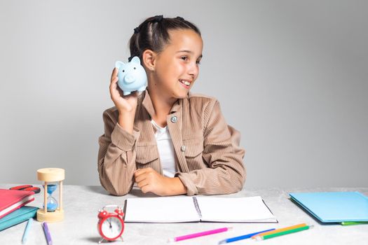 education, school and money saving concept - child putting coins into piggy bank