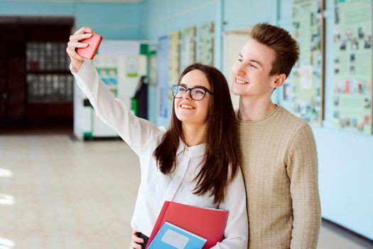 Two smiling students taking selfie in the university building, having nice time together