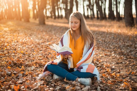 Cheerful girl in park with a book