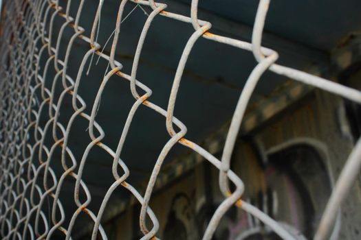 Rusty metal mesh close-up on the background of painted walls.