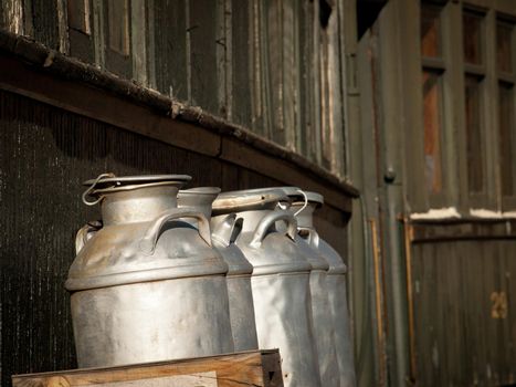 Old milk containers sit upon a typical freight mover at the local railroad station.