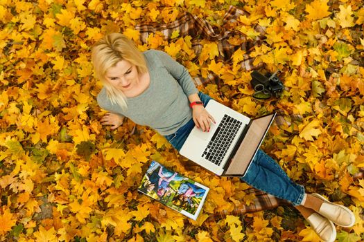 woman with laptop and photo book in autumn park.