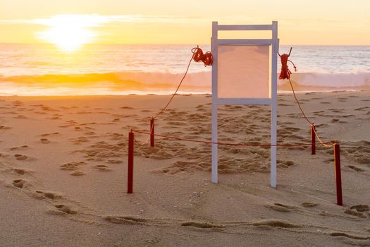 White information board on the beach at sunset