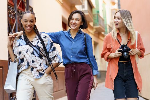 Carefree diverse female friends in elegant clothes going home after spending free time together in city