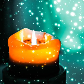 Happy holidays, greeting card and winter season concept - Orange holiday candle on green sparkling snowing background, luxury branding design for Halloween, New Years Eve and Christmas