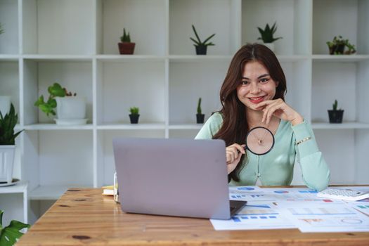 A half-bred girl, an audit employee, an accountant holding a magnifying glass and using a calculator to check the financial statement documents to calculate the annual tax payment to the IRS.