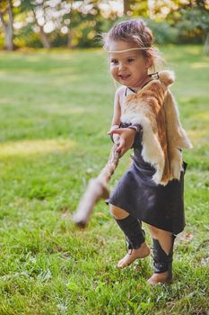 Cute baby dressed in the clothes of primitive people with combat staff.