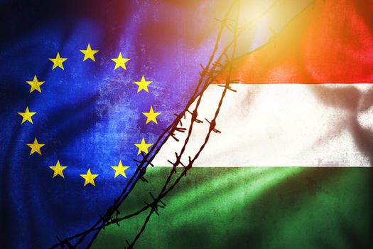 Grunge flags of EU and Hungary divided by barb wire illustration sun haze view, concept of tense relations between and dispute of European union and Hungary