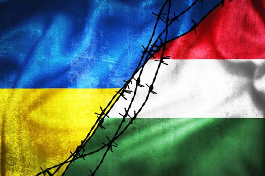 Grunge flags of Ukraine and Hungary divided by barb wire illustration, concept of tense relations between two countries