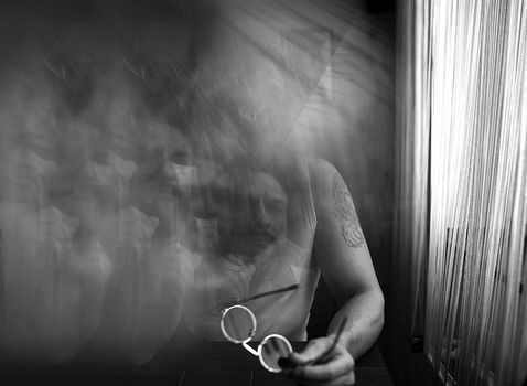the man's face is hidden by fog or smoke as if from cigarette smoke in a small room black and white photo. High quality pthe man's face is hidden by fog or smoke as if from cigarette smoke in a small room black and white photohoto