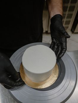 Decorator using spatula and scraper to smooth buttercream on a frosted cake