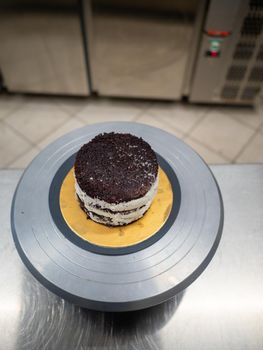 Decorator using spatula and scraper to smooth buttercream on a frosted cake