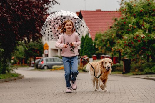 Preteen girl with golden retriever dog running outdoors together. Pretty kid child with purebred pet doggy at street