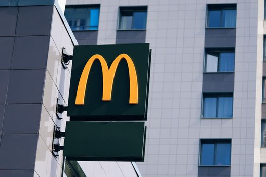 McDonald's street sign. McDonald's is global cafe chain that specializes burgers menu restaurant. Logo on facade of fast food diner. Saint-Petersburg, Russia - August 31, 2021