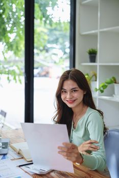 A businesswoman, an accountant, half girl,showing a smiling face while working on financial documents and using computers to check taxes and budgets for internal company spending.