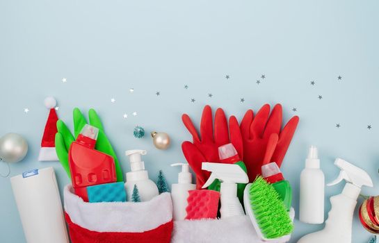 Christmas cleaning. Cleaning tools and Christmas decorations top view flat lay on blue background with copy space
