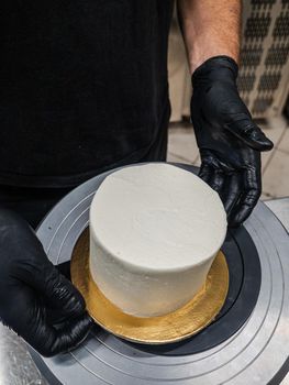 Decorator using spatula and scraper to smooth buttercream on a frosted cake