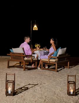 A couple of men and women having a romantic dinner on the beach in the evening. Asian women and Caucasian men having dinner on the beach of Huahin Thailand