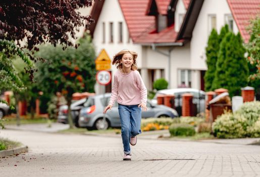Preteen girl running outdoors and smiling. Cute pretty child kid having fun at street