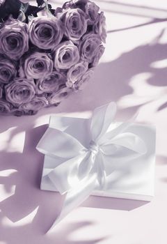 Happy holidays, luxe shopping and love gifts concept - Luxury holiday silk gift box and bouquet of roses on purple background, romantic surprise and flowers as birthday or Valentines Day present