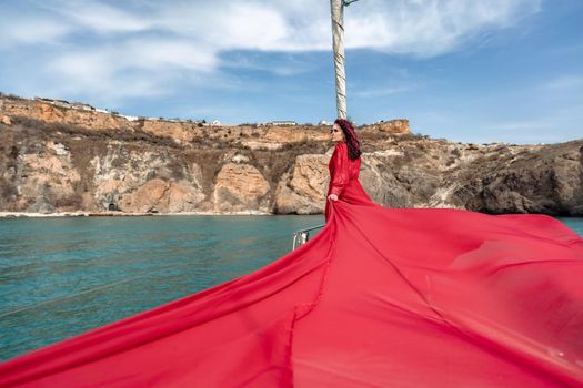 Attractive middle-aged woman in a red dress on a yacht on a summer day. Luxury summer adventure, outdoor activities