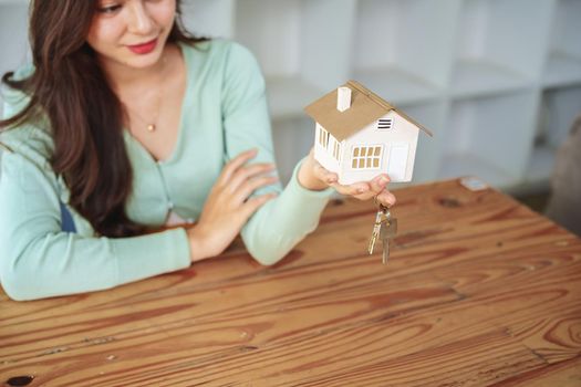 The customer holds the house model and keys after agreeing to invest in the housing purchase.