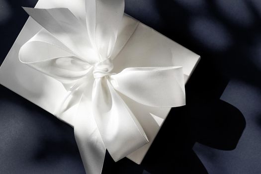 Anniversary celebration, shop sale promotion and luxe surprise concept - Luxury holiday white gift box with silk ribbon and bow on black background, luxe wedding or birthday present