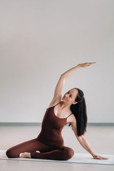 a woman in a brown suit does yoga in a fitness room . Healthy lifestyle, fitness, training, self-care.