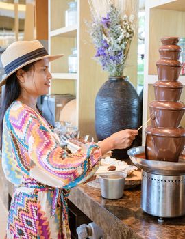 chocolate fountain, Asian women by a chocolate bar. a chocolate bar in a restaurant