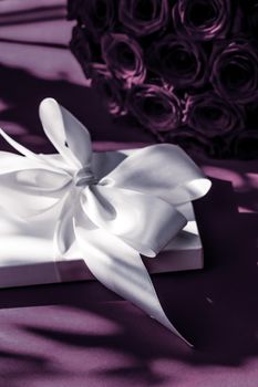 Happy holidays, luxe shopping and love gifts concept - Luxury holiday silk gift box and bouquet of roses on purple background, romantic surprise and flowers as birthday or Valentines Day present