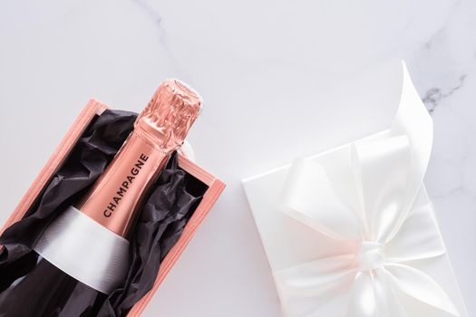 Celebration, drink and branding concept - Champagne bottle and gift box on marble, New Years, Christmas, Valentines Day or wedding holiday present and luxury product packaging for beverage brand