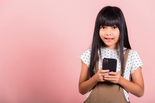 Asian kid 10 years enjoying using mobile phone for social network media at studio shot isolated on pink background, Happy child girl lifestyle using smartphone, typing message chatting with friend