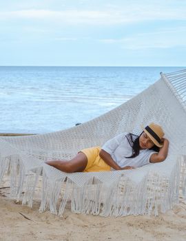women sleeping in a hammock on a beach in Thailand, Asian women taking a nap in the afternoon.