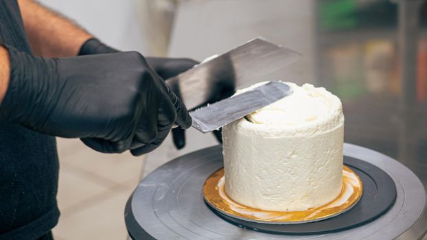 professional baker decorating a chocolate and cream cake with salty caramel